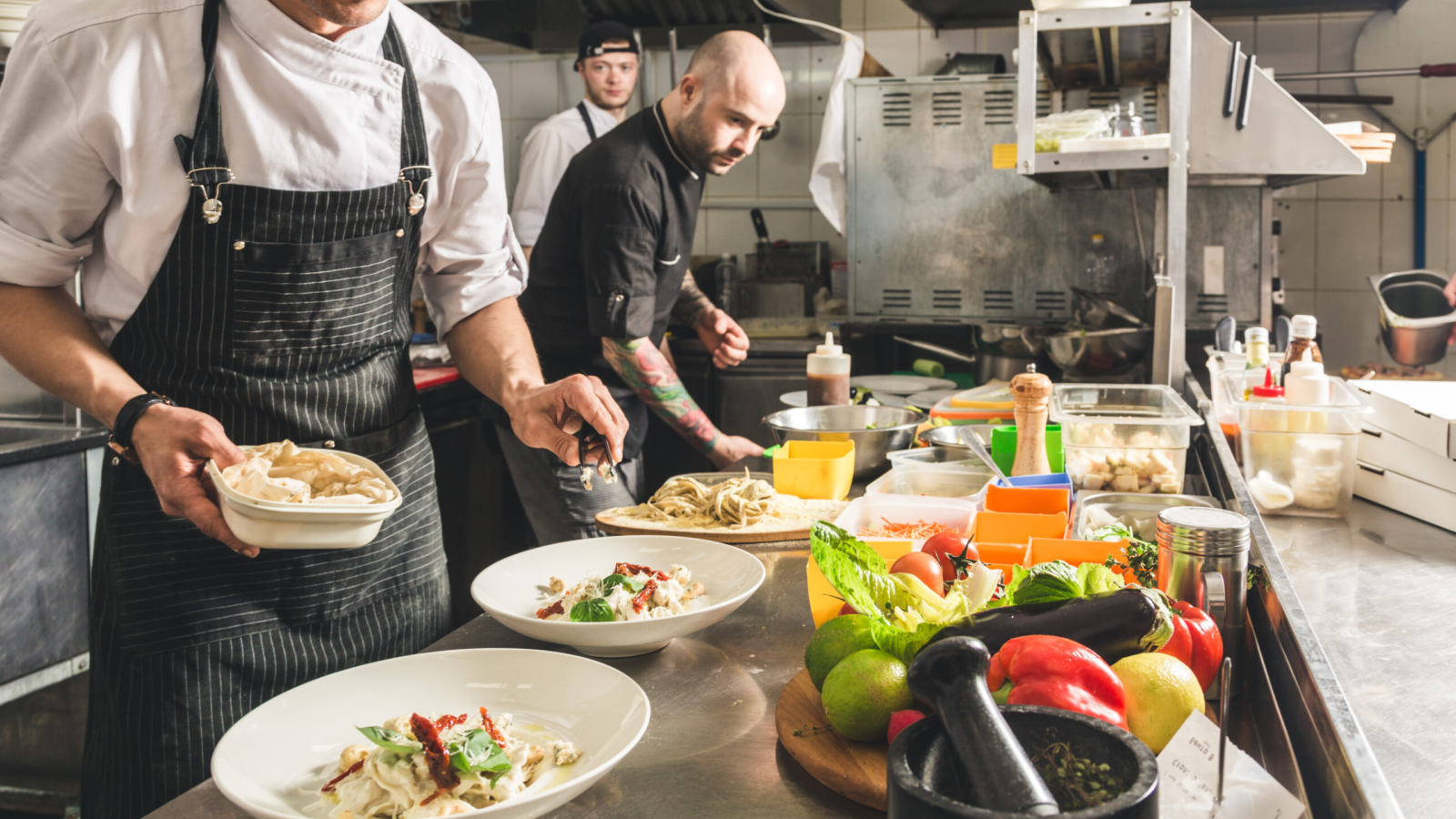 Professional chef cooking in the kitchen restaurant at the hotel, preparing dinner. A cook in an apron makes a salad of vegetables and pizza