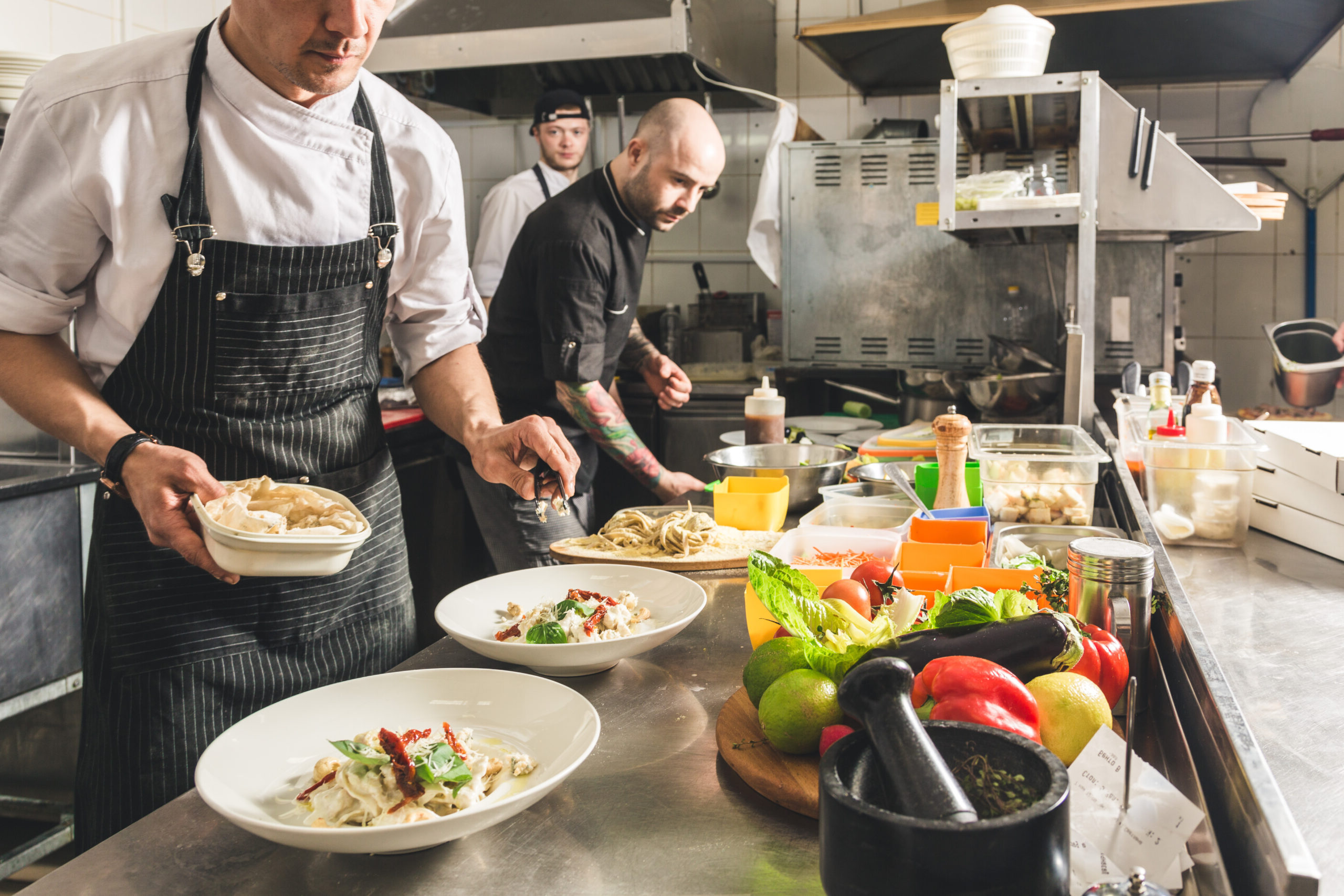 Professional chef cooking in the kitchen restaurant at the hotel, preparing dinner. A cook in an apron makes a salad of vegetables and pizza