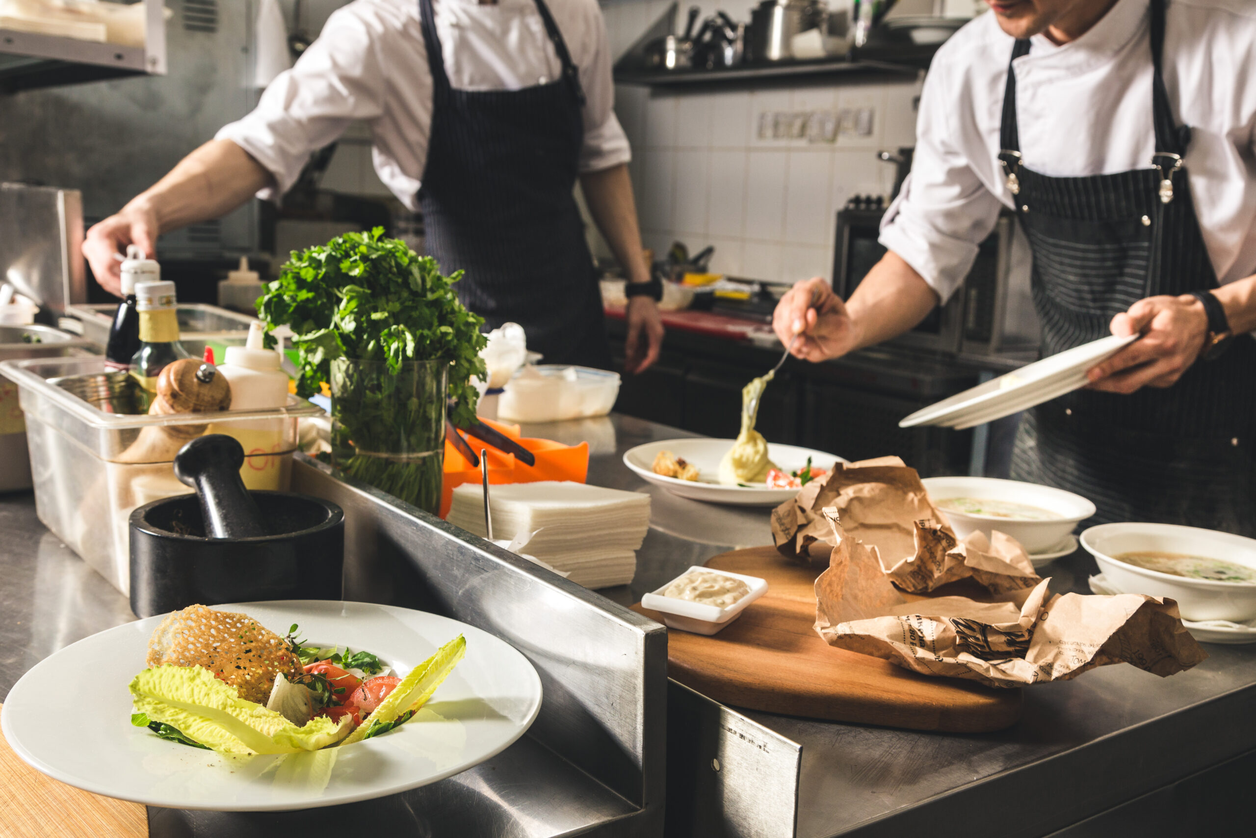 Professional chef cooking in the kitchen restaurant at the hotel, preparing dinner. A cook in an apron makes a salad of vegetables and pizza